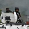 Members of the Bolivarian National Guard (GNB) sit on an armored vehicle in front of the Tocoron prison