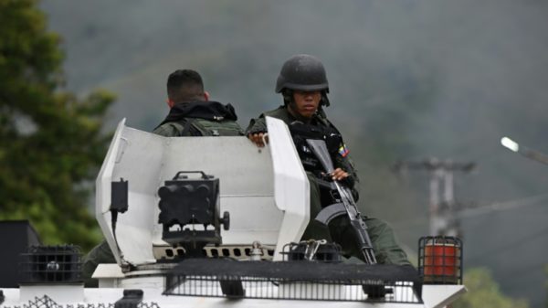 Members of the Bolivarian National Guard (GNB) sit on an armored vehicle in front of the Tocoron prison