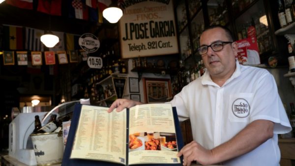 Carlos Fionda, 59, manager of Amazem Sao Thiago bar, shows of the physical menu at the Lapa neighborhood in Rio de Janeiro, Brazil, in May 2023.