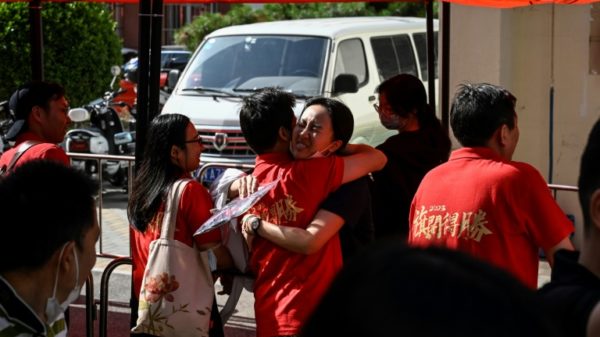 A student (C) hugs her teacher before entering the school on the first day of China's national college entrance examination, known as the gaokao, in Beijing on June 7, 2023.